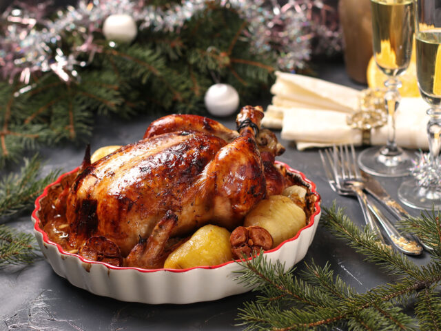 Baked chicken with orange, honey, soy sauce, onion and garlic in ceramic form on christmas background, horizontal orientation, closeup
